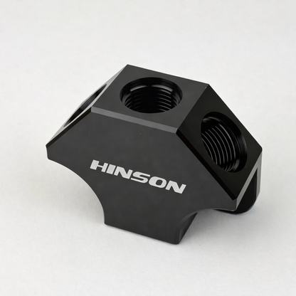 HINSONMotorsports billet Y-block fuel manifold lifestyle photo, front angle showing CNC machined detail, inlet and outlet ports, black anodized finish